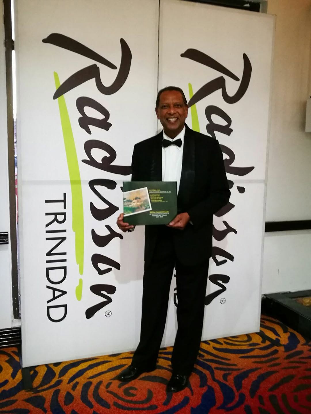 Seeram Ken Maharaj holding the commemorative book he edited